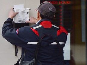 A mail carrier delivers mail in Ottawa, on Dec. 11, 2013.