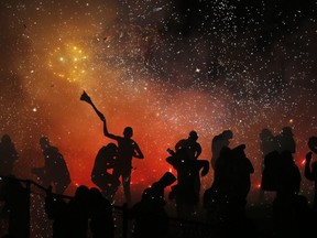 Revelers play around a huge burning papier mache bull full of exploding fireworks, in the Santiago Teyuhalco neighbourhood of Tultepec, Mexico, July 30, 2018.