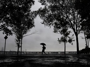 A person holds an umbrella while walking under light rain along the Hudson River waterfront on a dreary fall morning, Tuesday, Sept. 25, 2018, in Hoboken, N.J.