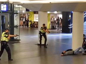 Dutch police officers point their guns at a wounded 19-year-old man who was shot by police after stabbing two people in the central railway station in Amsterdam, the Netherlands, Friday Aug. 31, 2018.