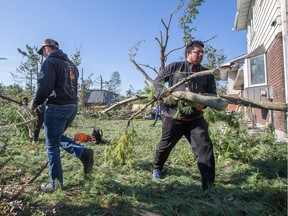 Volunteers and neighbours pitch in to remove debris from Parkland Cres home in the Arlington Woods neighbourhood as the region continues to deal with the after effects of the tornados that struck the region on Friday.