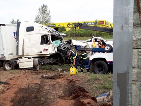 Workers prepare a transport truck for removal after it crashed through the Highway 401 sound barrier on Waverly Drive in Brockville, Ont. on Wednesday morning, Sept. 19, 2018.