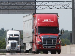 Transport trucks travel along Highway 401.