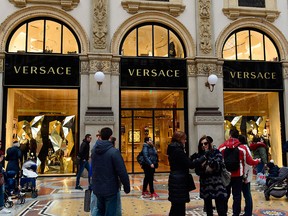 In this file photo taken on Dec. 4, 2017, people walk past Italian fashion shop Versace in the Vittorio Emanuele II Gallery in Milan.