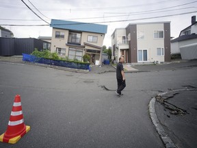 A resident walks by damaged houses in Kiyota, outskirts of Sapporo city, Hokkaido, northern Japan, Friday, Sept. 7, 2018.