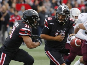 Second-year Ravens quarterback Mike Arruda hands the football to tailback Nathan Carter (31) during the first half of the Panda Game against the Ottawa Gee-Gees on Sept. 29.   Patrick Doyle/Postmedia