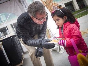 Mayor Jim Watson does his part by distributing sweets at the city hall party on Saturday. Ashley Fraser/Postmedia