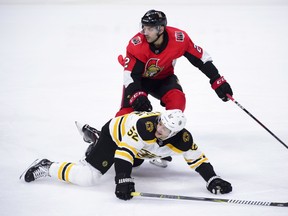 Ottawa Senators defenceman Dylan DeMelo pushes Boston Bruins centre Sean Kuraly to the ice during Tuesday's game. (THE CANADIAN PRESS)