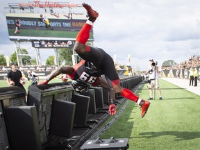 Redblacks’ A.C. Leonard goes flying over the sideline scoreboard after making a defensive play against the Hamilton Tiger-Cats on July 28. Friday’s tilt between the teams has major playoff implications. (CP FILE)