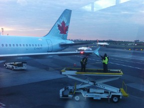 Runway crew members examine the wing tip of an Air Canada plane which arrived at LaGuardia Airport in New York on Monday, Oct. 22, 2018. An Air Canada flight that had just landed at New York's LaGuardia Airport late Monday afternoon was damaged as it sat on the taxiway by another passing plane. (THE CANADIAN PRESS/HO - Tim Clark)