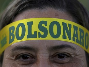 A supporter of presidential front-runner Jair Bolsonaro wears a headband supporting his candidate as he waits with others for election results outside the National Congress in Brasilia, Brazil, Sunday, Oct. 28, 2018. Brazilian voters decide who will next lead the world's fifth-largest country, the left-leaning Fernando Haddad of the Workers' Party, or far-right rival Bolsonaro of the Social Liberal Party.