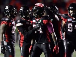 Linebacker Kyries Hebert, middle, celebrates with teammates after the Redblacks finally secured victory against the Ticats on Friday night and moved back alone atop the CFL East standings.