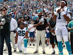 Carolina Panthers defensive back Eric Reid (25) kneels as quarterback Cam Newton (1) and others stand during the national anthem before Sunday's game against the Giants.