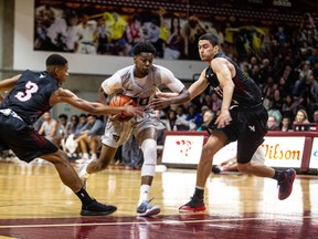 Ottawa’s Brandon Robinson tries to split Raven defenders T.J. Lall and Brandon Robinson during Carleton’s blowout win in their OUA men’s basketball opener last night on Friday at Montpetit Hall. The Ravens won 86-69. (Liam Mahoney)