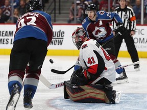 Ottawa Senators goaltender Craig Anderson, center, stops a shot off the stick of Colorado Avalanche left wing Gabriel Landeskog, front, as center Nathan MacKinnon looks on in the third period of an NHL hockey game Friday, Oct. 26, 2018, in Denver. The Avalanche won 6-3.