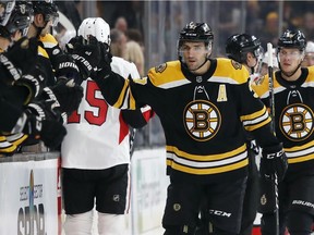 Boston's Patrice Bergeron is congratulated at the bench after scoring a first-period goal against the Senators on Monday. Bergeron finished the contest with three goals and an assist.