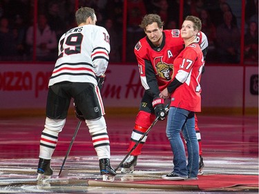 With Jonathan Toews, left, and Mark Stone looking on, Tina Boileau looks skyward after hearing her son, Jonathan Pitre, on the jumbo screen just before the ceremonial puck drop before the Ottawa Senators' season opener against Chicago at the Canadian Tire Centre on Thursday, Oct. 4, 2018.