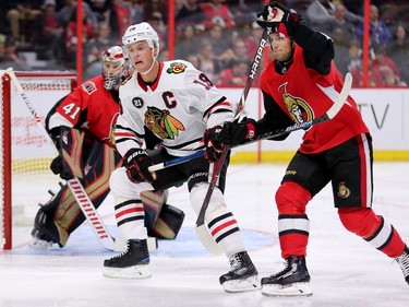 Chris Wideman attempts to tie up 'Hawks captain Jonathan Toews in front of goalie Craig Anderson in the second period.