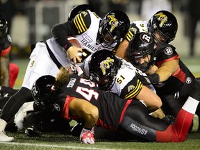 Tiger-Cats’ Dane Evans looks for extra yardage via the quarterback sneak as Ticats and Redblacks players pile on during last night’s contest in Ottawa. (THE CANADIAN PRESS/PHOTO)