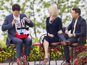 Prime Minister Justin Trudeau, left, holds up a pair of socks that he received as a gift from Kelly Ripa, centre, and Ryan Seacrest during his appearance on Live with Kelly and Ryan in Niagara Falls, Ontario on Monday, June 5, 2017.