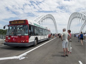 People look on as a OC Transpo bus carrying VIPs is the first vehicle to roll across the bridge connecting Barrhaven and Riverside South on Saturday, July 12, 2014.
