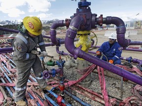 In this March 29, 2013 file photo, workers tend to a well head during a hydraulic fracturing operation at an Encana Oil & Gas (USA) Inc. gas well outside Rifle, in western Colorado.