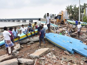 Indian people look at debris of boats in Velankanni in India's southern Tamil Nadu state on November 16, 2018, after a cyclone struck the region. - At least 11 people were reported dead on November 16 as a powerful cyclone battered India's eastern coast, authorities said.