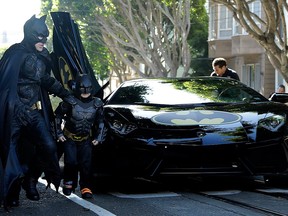 Miles Scott, dressed as Batkid, second from left, exits the Batmobile with Batman to save a damsel in distress in San Francisco, Friday, Nov. 15, 2013.