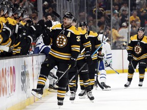 Bruins centre Patrice Bergeron is congratulated by teammates on the bench after scoring against the Maple Leafs during the first period in Boston on Saturday night. (Winslow Townson/The Associated Press)