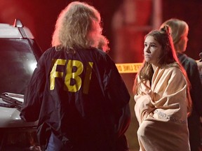 An FBI agent talks to a potential witness as they stand near the scene Thursday, Nov. 8, 2018, in Thousand Oaks, Calif. where a gunman opened fire inside a country dance bar crowded with hundreds of people.