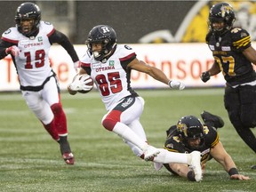 Wearing the Redblacks' white "away" jerseys, Diontae Spencer runs for a gain during an Oct. 27 game against the Ticats in Hamilton.