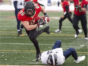 Laval's Vincent Forbes-Mombleau dives over St. Francis Xavier's Johnny Obdam into the end-zone for a touchdown during the Uteck Bowl game at Quebec City on Saturday.