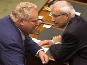 Premier Doug Ford (left) speaks with Finance Minister Vic Fedeli as the Ontario legislature holds a midnight session to debate a bill that would cut the size of Toronto city council on Sept. 17, 2018. (THE CANADIAN PRESS)