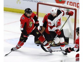 Ottawa Senators defenseman Cody Ceci (5) and New Jersey Devils right wing Joey Anderson (49) battle for the loose puck in front of Ottawa Senators goaltender Craig Anderson (41) during third period NHL hockey play in Ottawa Tuesday November 6, 2018 .