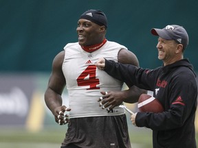 Calgary Stampeders defensive tackle Micah Johnson (left) and head coach Dave Dickenson have a laugh during practice earlier this week. (Jason Franson/The Canadian Press)