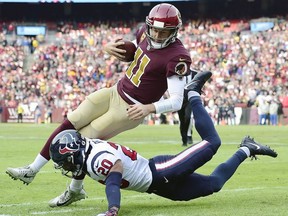 Alex Smithof the Washington Redskins is tackled by Justin Reid of the Houston Texans in the first half at FedExField on November 18, 2018 in Landover, Maryland.
