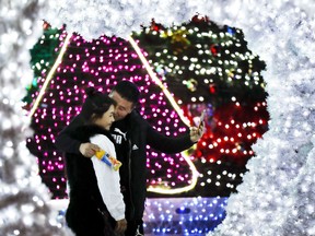 A man kisses his partner as they take a selfie near light installation decorated for the Christmas season outside an office building in Beijing, Thursday, Dec. 1, 2016. A city in northern China has been stripped of Christmas cheer after the authorities banned all festive decorations from its streets.