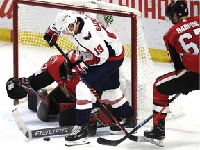 Ottawa Senators goaltender Mike McKenna (33) uses his stick to control the puck in the crease as defenceman Ben Harpur (67) tries to force back the stick of Washington Capitals centre Nicklas Backstrom.