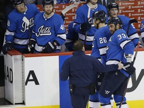 Winnipeg Jets' Dustin Byfuglien (33) is assisted off the ice by Blake Wheeler (26) and a trainer during third period NHL action against the Minnesota Wild in Winnipeg on Saturday. Byfuglien did not return to the game.