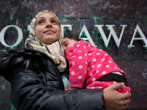 Kaffa Alwane's smile was evident as she was told "welcome home" by a volunteer upon arriving with her one-year-old daughter, Saloa, and her husband. A couple of dozen Syrian refugees, who seemed tired but happy, arrived at Ottawa's airport Tuesday (Dec. 29, 2015) to a welcoming group of volunteers handing out gifts. The group was taken from the airport in a bus to downtown, but not before feeling the chill of the capital's first winter snowstorm.