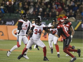 Redblacks linebacker Kyries Hebert (34) and Stampeders receiver Eric Rogers watch a tipped football fly through the air during the Grey Cup game at Edmonton on Nov. 25.