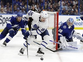 The Toronto Maple Leafs' Andreas Johnsson controls the puck at the side of the Tampa Bay Lightning net with Dan Girardi in pursuit and goaltender Andrei Vasilevskiy watching.