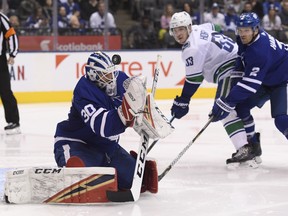 Maple Leafs goaltender Michael Hutchinson (30) makes a save as Maple Leafs defenceman Ron Hainsey (2) and Vancouver Canucks centre Bo Horvat (53) look on during second period in Toronto on Saturday. THE CANADIAN PRESS/Nathan Denette