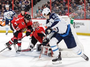 Anders Nilsson of the Ottawa Senators makes a pad save on a wraparound attempt by Mark Scheifele #55 of the Winnipeg Jets as Christian Jaros #83 of the Ottawa Senators defends the net in the first period on Saturday afternoon at the CTC.