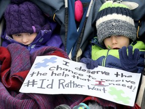 Amara LeBlanc, 4, and her friend Kevin Maillot, 4, sit in a stroller while their parents protest outside the Barrhaven constituency office of Social Services minister Lisa MacLeod