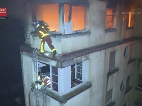 In this image taken from video released by the Paris Fire Dept., firemen scale the top floors of an apartment building on fire, Tuesday, Feb. 5, 2019, in Paris, France.