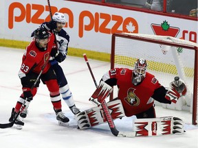 Ottawa Senators goaltender Anders Nilsson (31) makes a glove save defenceman Christian Jaros (83) checks Winnipeg Jets centre Mark Scheifele (55) during third period NHL hockey action in Ottawa on Saturday, February 9, 2019.