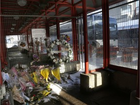 A bus runs through the Westboro station on Friday, passing a collection of items placed there in memory of the victims of the Jan. 11 double-decker bus crash.