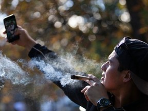 A man takes a selfie as he smokes a marijuana cigarette during a legalization party at Trinity Bellwoods Park in Toronto, Ontario, October 17, 2018.