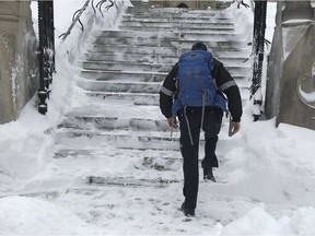 A parliamentary security officer climbs over a huge snowbank and up stairs to get to work on Feb. 13, 2019 in Ottawa.